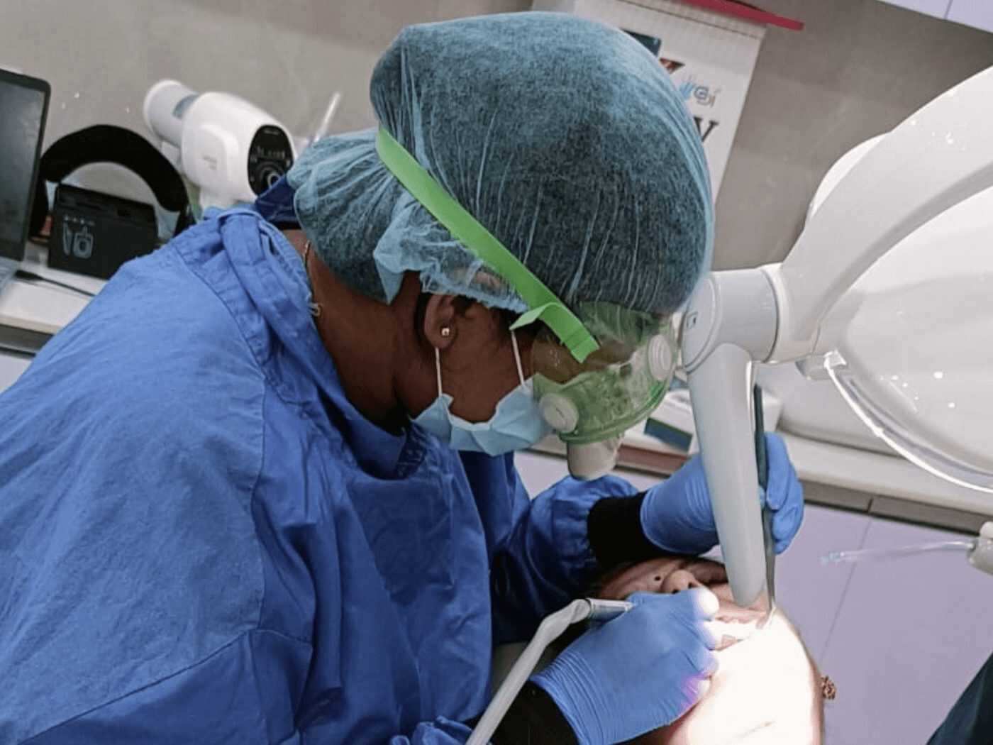 A dentist treating a patient under magnification in the operatory at Mahavirai Dental