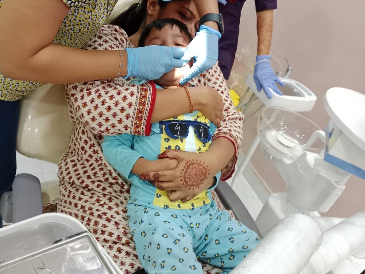 A young child being treated on a parent's lap at Mahavirai Dental, Gurgaon
